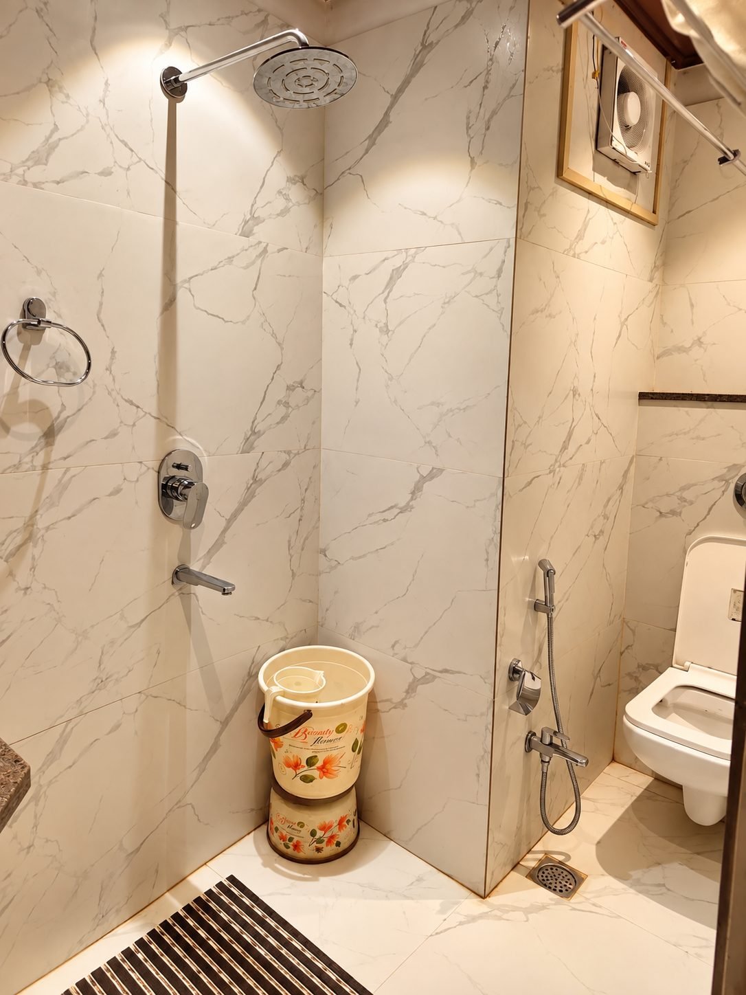 Deluxe room bathroom with white marble-effect tiles and a rain shower